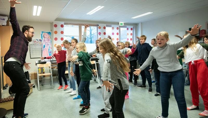 Elever danser i klasserommet.